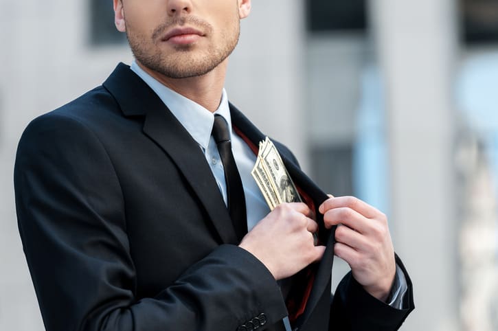 Cropped shot of a businessman placing money into his pocket